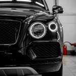 Bentley front exterior detailed by AYB Detailing, showcasing polished headlight, grille, and glossy black paint with deep reflection and mirror-like finish.