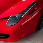 Close-up of a red Ferrari headlight and front fender after professional stainless steel polishing and detailing by AYB Detailing.